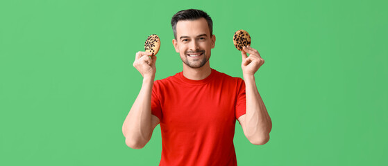 Fototapeta premium Handsome man with tasty cookies on green background