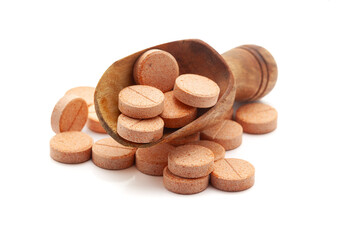 Health care concept. A wooden scoop filled With Orange Medical Pills and Tablets. Isolated on a...