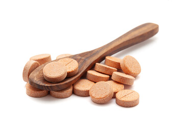 Health care concept. A wooden spoon filled with Orange Medical Pills and Tablets. Isolated on a white background.