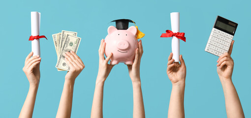 Female hands holding diplomas, money, calculator and piggy bank with graduation hat on blue...