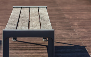 The shadow of an old bench placed on an outdoor terrace.
