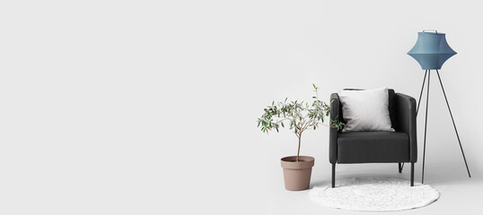 Black armchair with lamp and houseplant on white background
