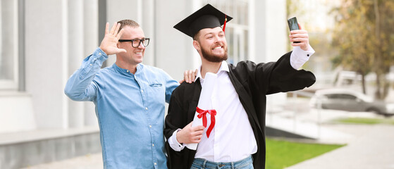 Happy young man with his father taking selfie on graduation day