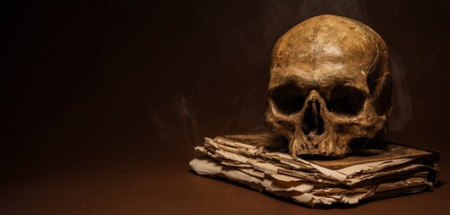 Human skull with old book on dark brown background with space for text