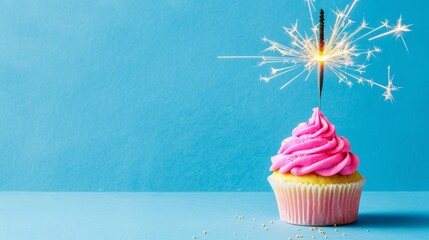   A cupcake with pink frosting, a sparkler sticking out its side, against a blue background