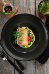 Grilled cod fillet with steamed vegetables. A healthy dietary fish dish served on a wooden table,...