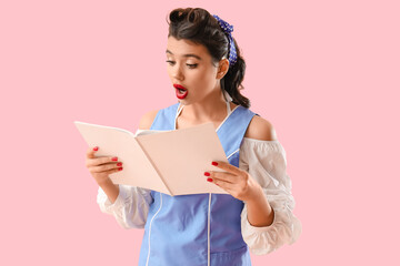 Fototapeta premium Young pin-up woman reading magazine on pink background