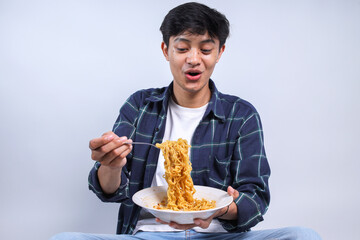 Portrait Of Excited Young Asian Man Pull The Spicy Noodles Isolated On White Background