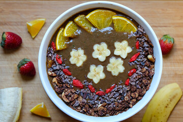 Healthy Raw Cacao chocolate smoothie bowl topping with cacao nibs and cacao granola goji berry banana and orange 