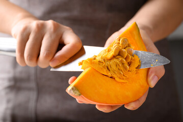 Orange Hokkaido pumpkin with hand holding knife for remove seed, Homemade cooking