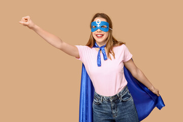 Young woman in superhero costume on beige background. Women's history month