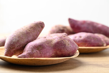 Raw purple sweet potatoes in wooden bowl with white background, Food ingredient