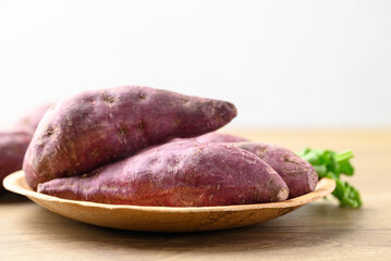 Raw purple sweet potatoes in wooden bowl with white background, Food ingredient