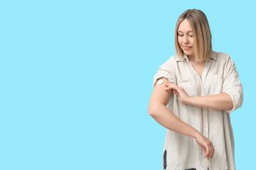 Woman with glucose sensor for measuring blood sugar level on blue background. Diabetes concept