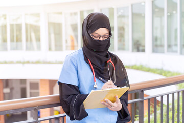 Female Muslim doctor in Abaya niqab traditional clothes works at modern clinic office checking of...