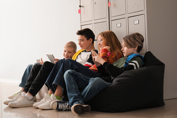 Little pupils using gadgets near locker at school - Powered by Adobe