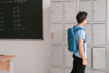 Little schoolboy near locker in classroom, back view