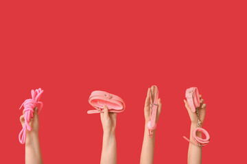 Female hands with toys from sex shop on red background