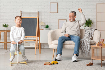 Grandfather and cute little boy playing with rocking horse at home