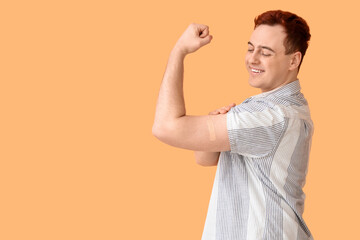 Young man showing strength symbol with applied medical patch on beige background. Vaccination...