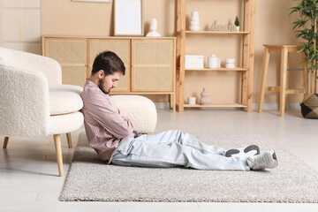 Tired young man sleeping on floor at home