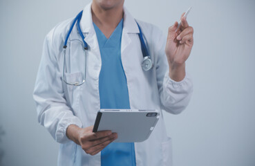 Mature male doctor with tablet pc is giving presentation. Blurred background indoors.
