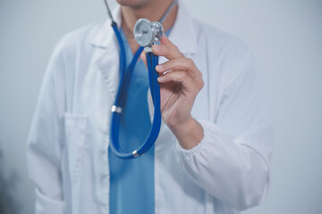 Senior doctor wearing white coat standing holding stethoscope in hands. Older male physician healthcare professional showing medical equipment ready to listen lungs or heart concept. Close up view