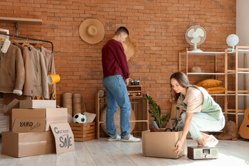 Young couple packing in room of unwanted stuff