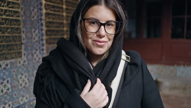 A smiling young woman with glasses stands before an ornate backdrop at the topkapi palace in istanbul, evoking a sense of cultural history and travel.