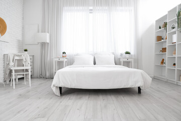 Interior of light bedroom with tables and window