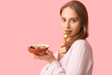 Young woman with bowl of healthy oatmeal on pink background