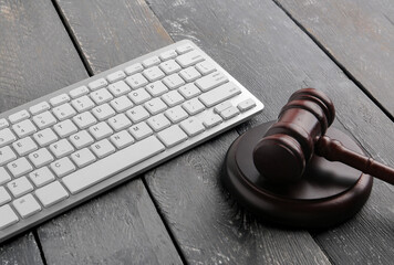 Modern keyboard and judge's gavel on dark wooden background, closeup