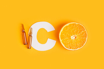 Paper letter C, ampules and orange on color background