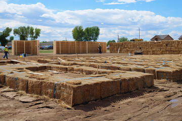 Contractors assemble straw bale walls, sustainable building with natural resources.