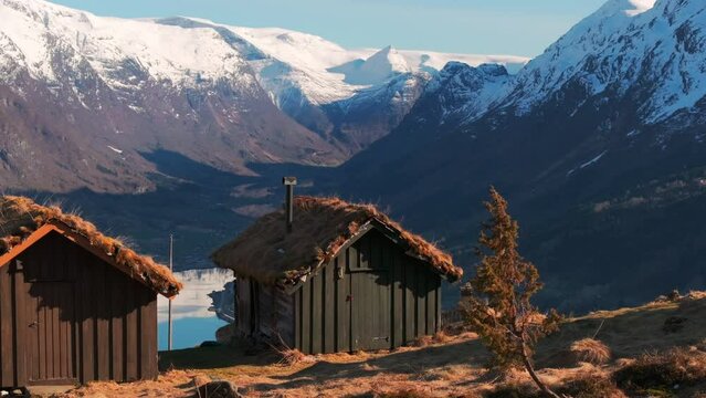 Drone reveal Norway glacier in sunset from remote idyllic mountainside cabins