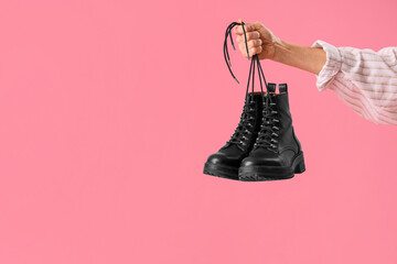 Hand of female shoemaker with shoes on pink background