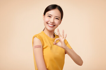 Healthy asian woman getting vaccinated immunity giving ok hand sign on beige background, concept of...
