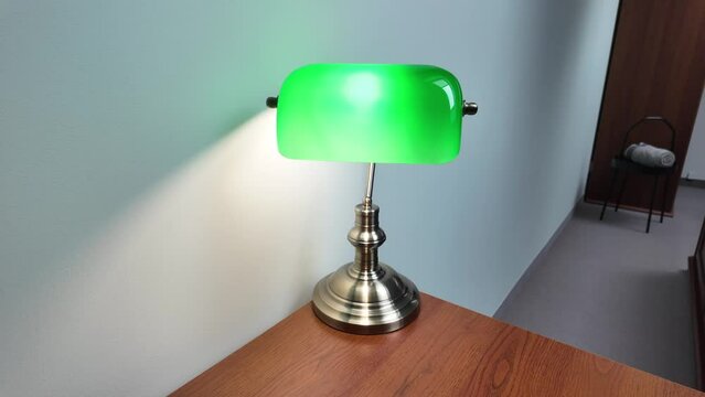 Green Reading Lamp On Wooden Desk In The Library. Slow zoom in.
