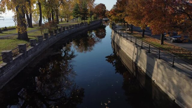 drone fly above the Lachine Canal in Montreal with tree reflection on still water 