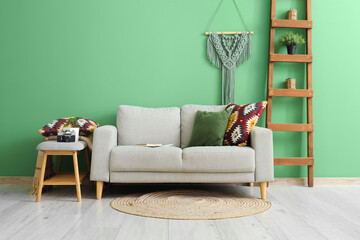Interior of green living room with cozy sofa, cushions and ladder
