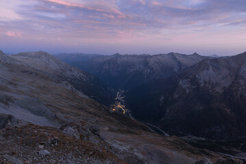 Aerial view at dusk of an Alpine valley with the lights of a mountain village. Macugnaga and the...