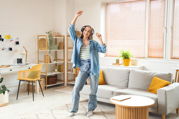 Young pretty woman in headphones dancing in light living room