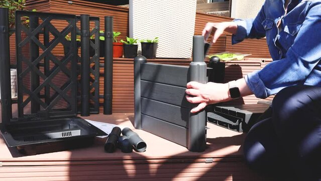 Woman in jeans shirt assemble plastic flower pot with trellis garden scheme, patio. Sunny day. High quality 4k video. 