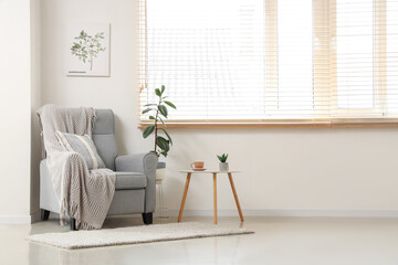 Interior of light room with grey armchair and table