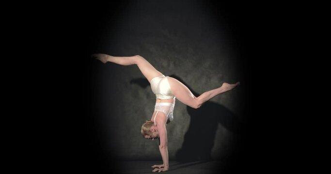 Artistic acrobat in spotlight does handstand with various leg poses