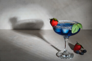 Glass of tasty cocktail with berries on grey table