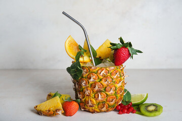 Tasty summer cocktail in pineapple with fruits on light table