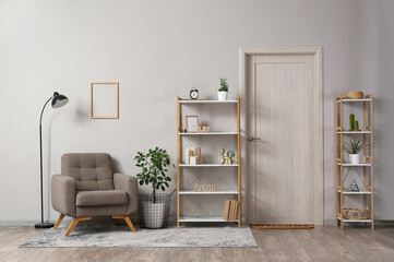 Interior of living room with lamp, armchair, houseplant and shelving units