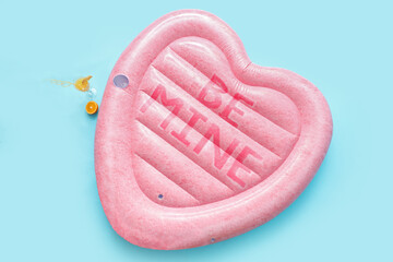 Inflatable mattress in shape of heart and cocktail on blue background