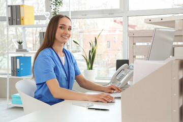 Female receptionist working with computer at desk in clinic